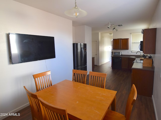 dining space featuring dark hardwood / wood-style flooring, rail lighting, and sink