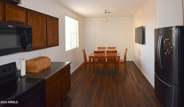 kitchen with dark wood-type flooring, black appliances, and decorative light fixtures