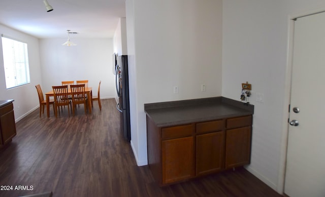 kitchen featuring pendant lighting, dark hardwood / wood-style flooring, and stainless steel refrigerator