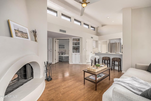 living room with hardwood / wood-style flooring, ceiling fan, a high ceiling, and built in shelves