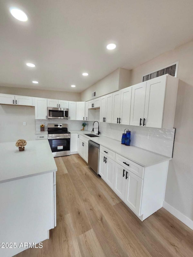 kitchen featuring white cabinetry, appliances with stainless steel finishes, light hardwood / wood-style floors, and sink