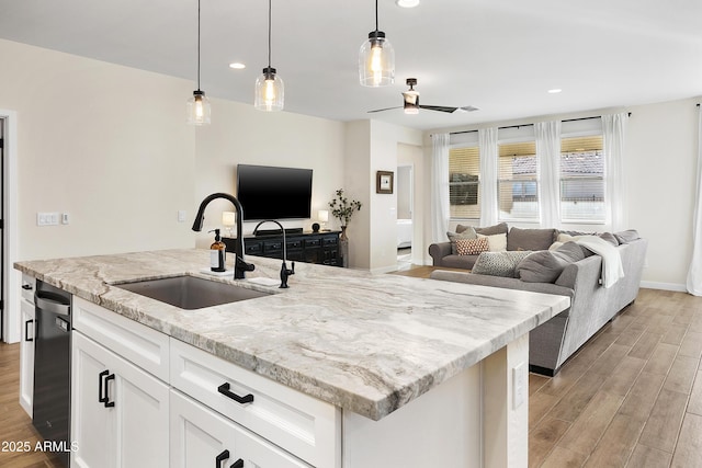 kitchen with hanging light fixtures, light stone countertops, sink, and white cabinetry