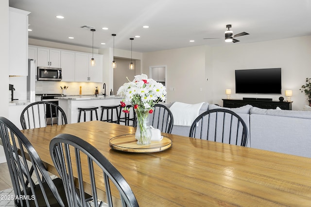 dining space featuring ceiling fan and sink