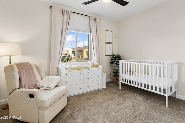 carpeted bedroom featuring ceiling fan and a crib