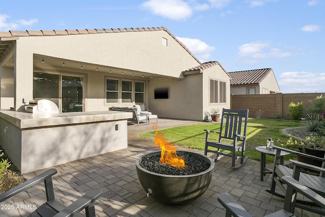 back of house featuring an outdoor fire pit, a yard, an outdoor kitchen, and a patio