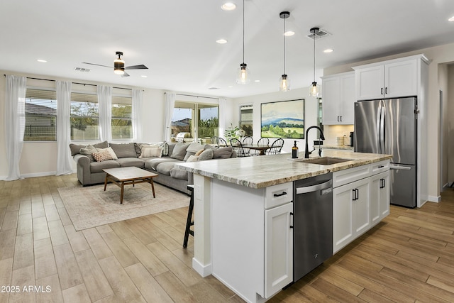 kitchen featuring white cabinets, appliances with stainless steel finishes, sink, and an island with sink