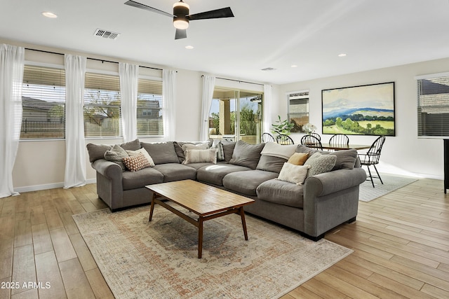 living room with ceiling fan, a wealth of natural light, and light hardwood / wood-style flooring