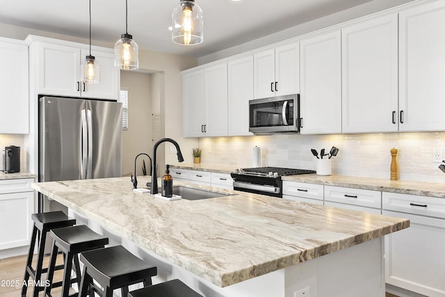 kitchen with sink, pendant lighting, stainless steel appliances, and white cabinetry