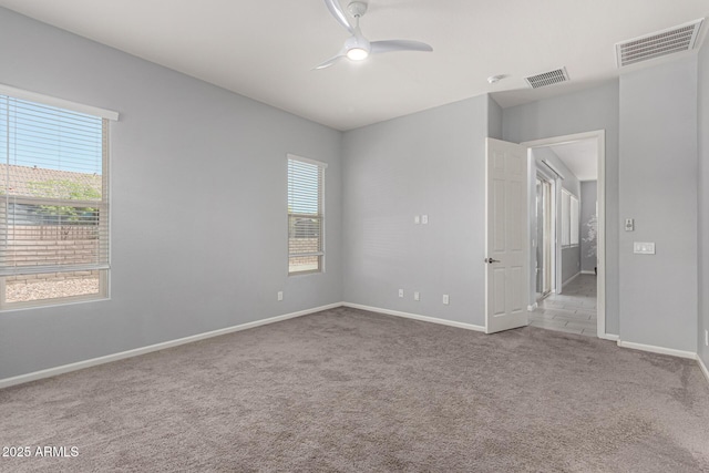 carpeted spare room with ceiling fan, visible vents, and baseboards