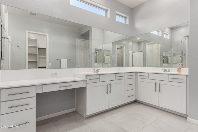 bathroom with double vanity, tile patterned flooring, a shower with shower door, and a sink