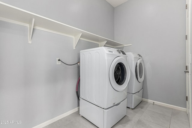 laundry room with laundry area, baseboards, light tile patterned floors, and washing machine and dryer