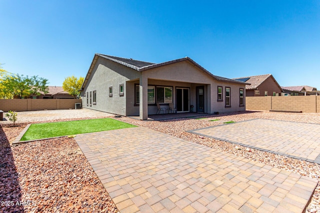 back of property featuring a yard, a patio, a fenced backyard, and stucco siding