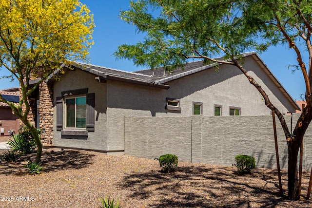 view of side of property featuring stucco siding and fence