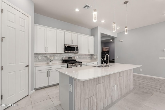 kitchen with visible vents, appliances with stainless steel finishes, tasteful backsplash, a sink, and light countertops