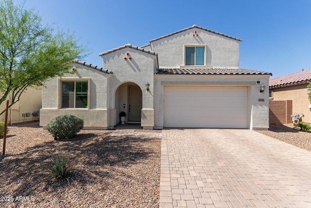 5330 W Thresher Way, Laveen, AZ 85339 - mediterranean / spanish home featuring a tile roof, decorative driveway, stucco siding, and an attached garage
