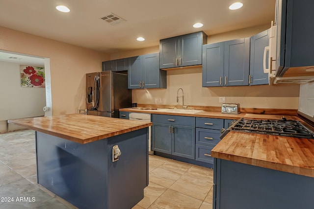 kitchen featuring a center island, sink, butcher block countertops, a kitchen bar, and stainless steel appliances