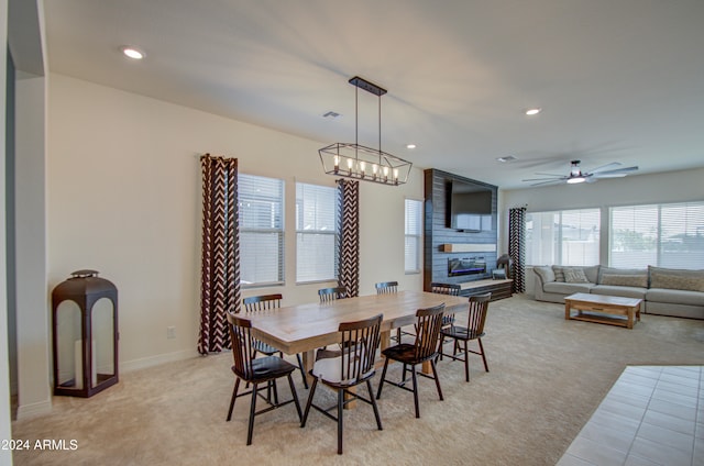 dining room with light colored carpet and ceiling fan with notable chandelier