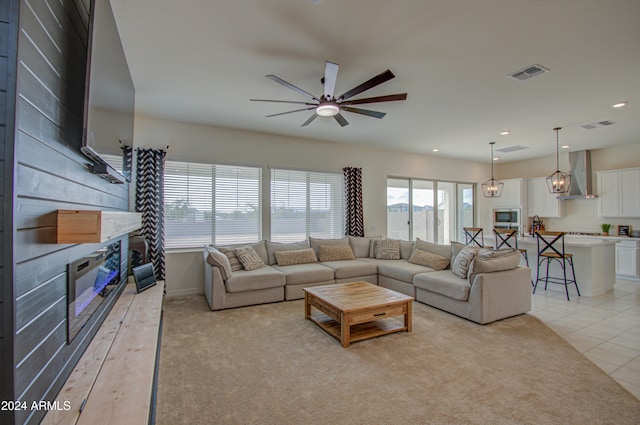 living room featuring light carpet and ceiling fan with notable chandelier