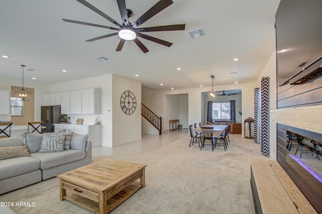 carpeted living room featuring ceiling fan with notable chandelier