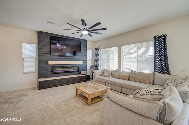 carpeted living room featuring a fireplace and ceiling fan