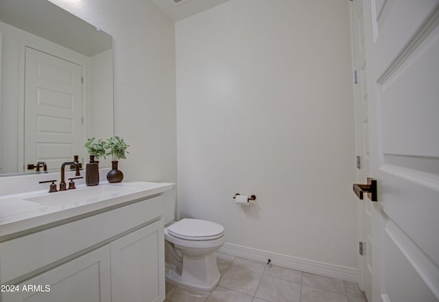 bathroom with toilet, vanity, and tile patterned floors