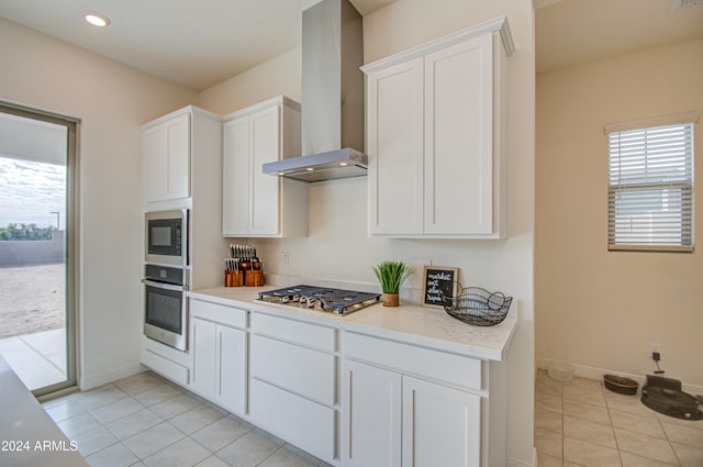 kitchen with white cabinetry, wall chimney exhaust hood, light tile patterned flooring, and stainless steel appliances