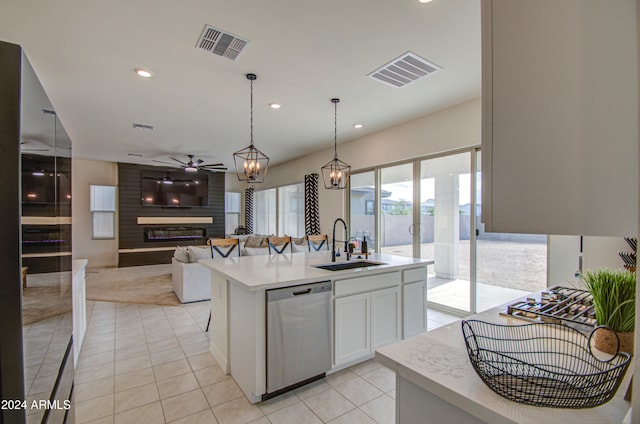 kitchen with a center island with sink, white cabinets, sink, stainless steel dishwasher, and ceiling fan