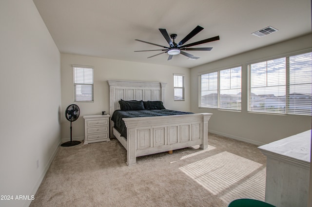 bedroom with ceiling fan, multiple windows, and light carpet