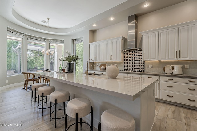 kitchen featuring visible vents, tasteful backsplash, wall chimney exhaust hood, and stainless steel gas cooktop