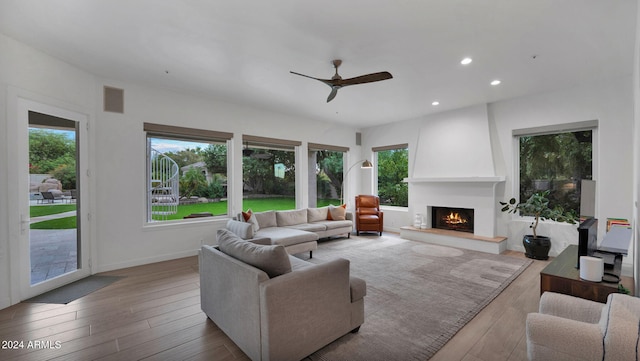 living room featuring ceiling fan, a large fireplace, and hardwood / wood-style floors