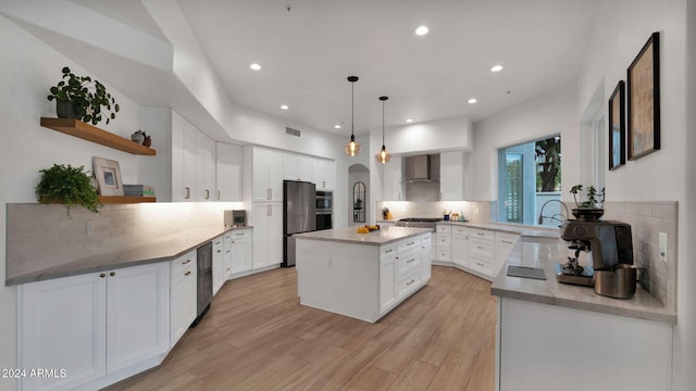 kitchen with hanging light fixtures, backsplash, white cabinets, wall chimney range hood, and a kitchen island