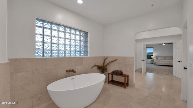 bathroom with tile walls, tile patterned flooring, and a bathing tub