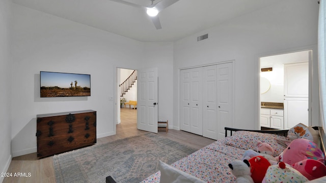 bedroom with ceiling fan, light hardwood / wood-style floors, a closet, and a towering ceiling