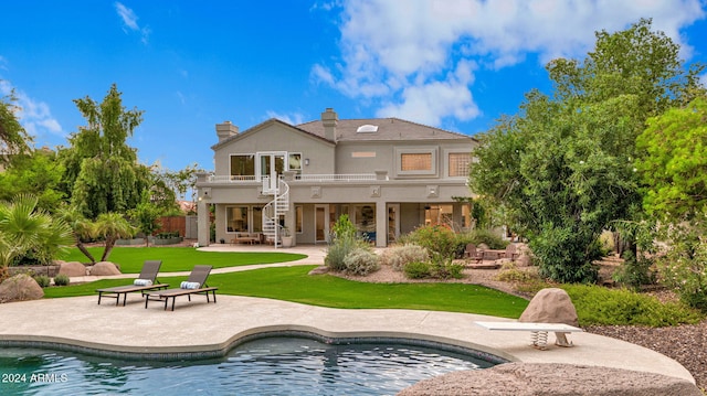 rear view of house with a balcony, a patio, and a yard