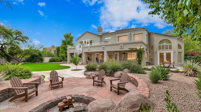 rear view of property featuring a balcony, an outdoor fire pit, a yard, and a patio