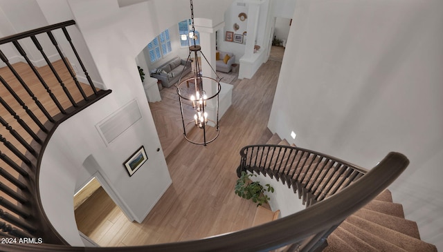 stairway with hardwood / wood-style floors and a chandelier