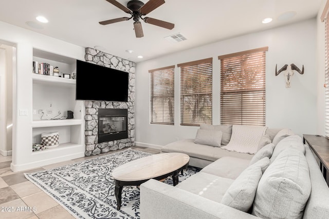 living room with plenty of natural light, built in features, and a stone fireplace