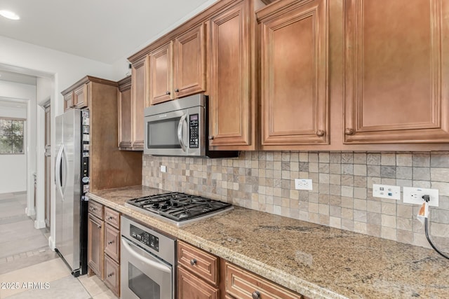 kitchen featuring light tile patterned floors, decorative backsplash, light stone counters, and stainless steel appliances