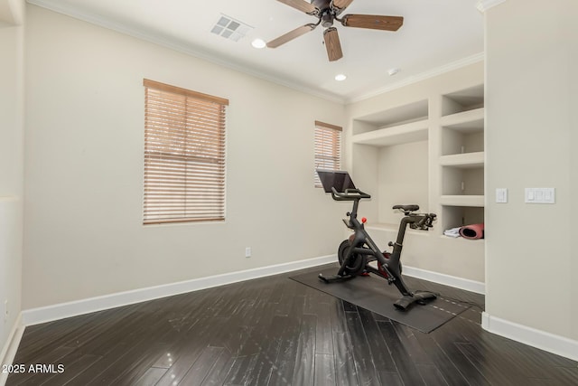 exercise room featuring dark wood-type flooring, crown molding, built in features, and ceiling fan