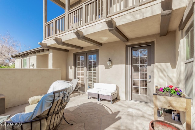 view of patio featuring a balcony, an outdoor hangout area, and french doors