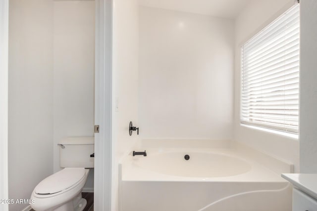 full bath featuring vanity, a garden tub, and toilet