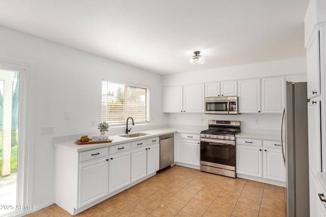 kitchen with a sink, appliances with stainless steel finishes, white cabinets, light countertops, and light tile patterned floors