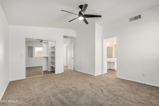 unfurnished bedroom featuring visible vents, lofted ceiling, a closet, carpet floors, and baseboards