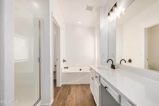 bathroom with visible vents, a stall shower, wood finished floors, a bath, and vanity