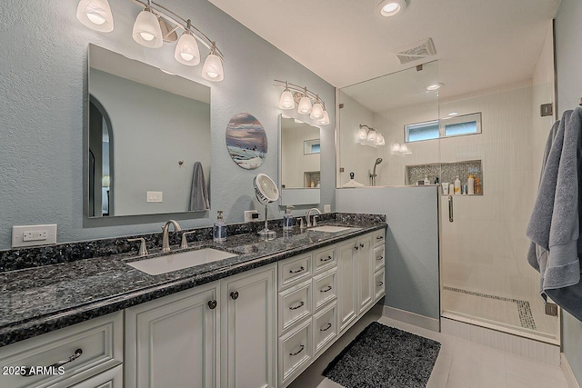 full bath featuring a stall shower, tile patterned flooring, a sink, and double vanity