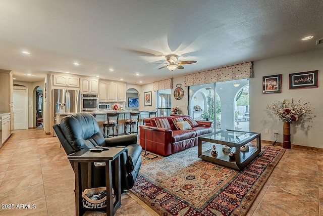 living area with arched walkways, ceiling fan, a textured ceiling, and recessed lighting