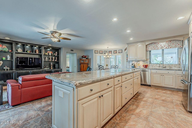 kitchen with ceiling fan with notable chandelier, stainless steel appliances, a sink, a center island, and decorative backsplash