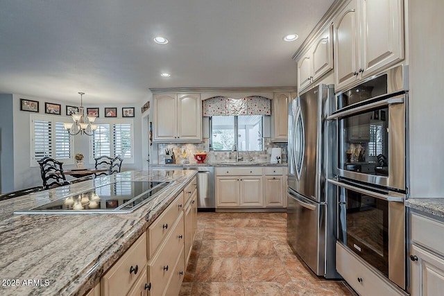 kitchen featuring appliances with stainless steel finishes, a healthy amount of sunlight, a sink, and tasteful backsplash