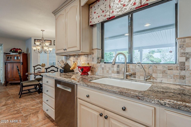 kitchen with stone counters, decorative backsplash, cream cabinets, stainless steel dishwasher, and a sink