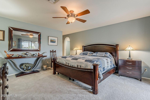 carpeted bedroom featuring baseboards, visible vents, arched walkways, and a ceiling fan